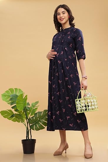 A pregnant woman gracefully poses wearing a navy blue floral printed midi dress, styled with nude heels and a chic handbag.