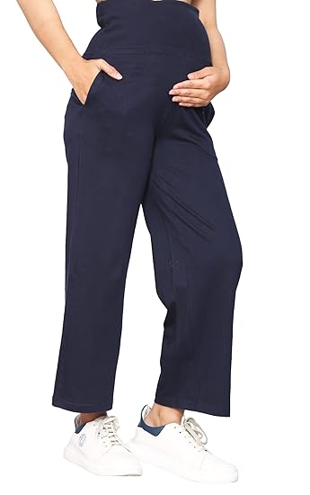 Pregnant woman wearing navy blue maternity palazzo pants with side pockets, paired with white sneakers, holding her baby bump.